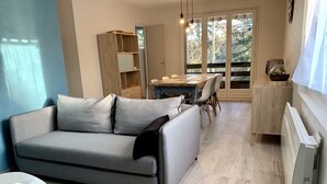 Un salon moderne avec un canapé gris, une table à manger et un coin cuisine doté de meubles en bois.