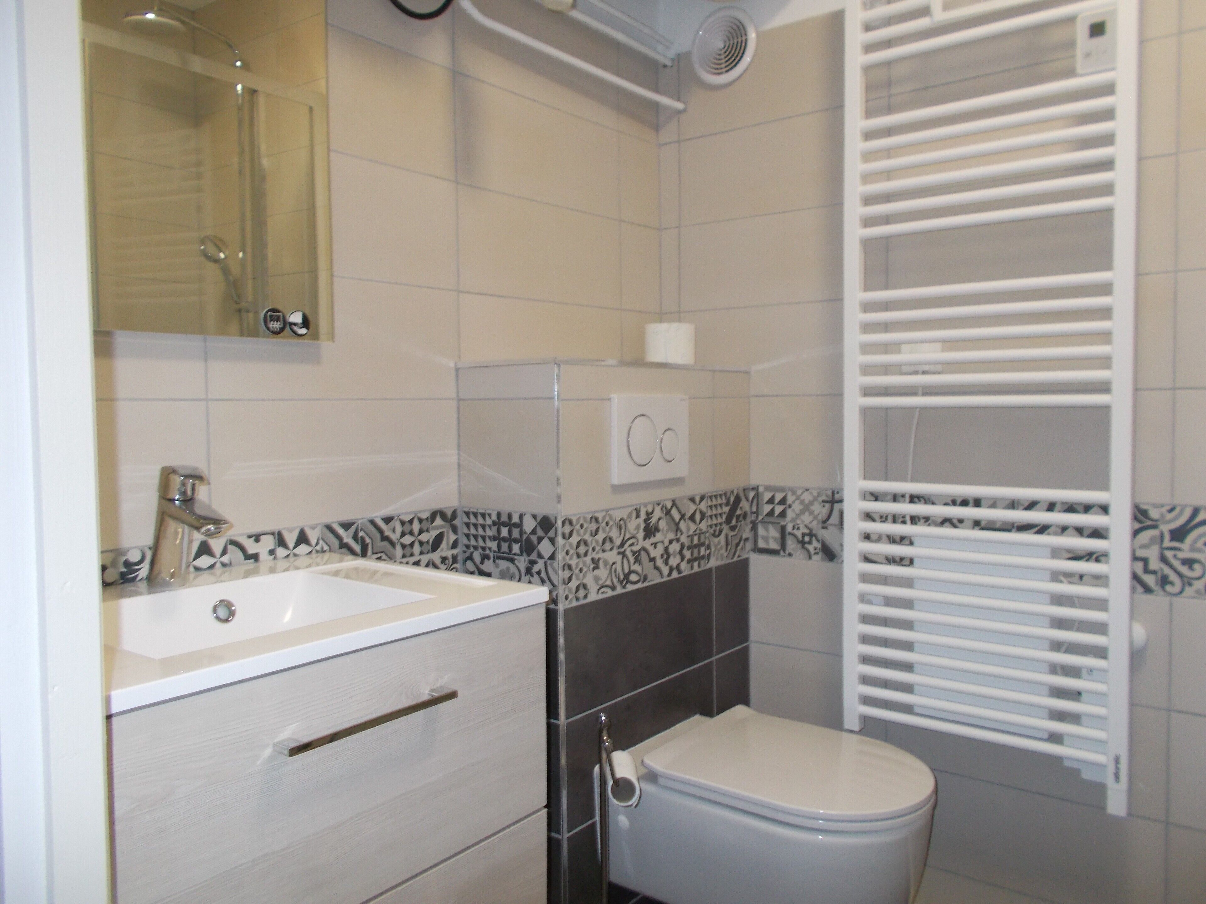Une salle de bain avec un lavabo blanc, des toilettes et une douche.