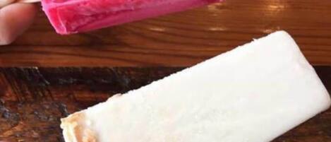 Deux bâtonnets de glace, l’un rose et l’autre blanc, posés sur une surface en bois.
