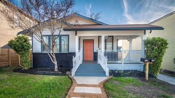 A two-story house with a front porch, a mailbox, and a small garden.