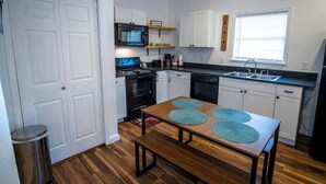 A compact kitchen with white cabinets, a black stove, a microwave, and a sink.