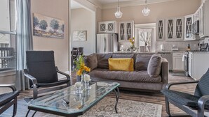 Una sala de estar moderna con una mesa de centro de vidrio, un sofá y un comedor con una cocina al fondo.
