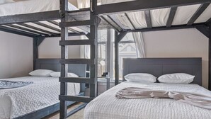 Una habitación con literas, una escalera y una ventana con cortinas.