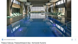 An indoor swimming pool with a modern design, featuring a long, narrow pool and seating areas on both sides. - Fully renovated apartment with direct sea access (100m) 2nd floor elevator (Cabourg)