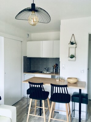 Et moderne køkken med en backsplash i sort og hvidt mønster, et træspisebord med fire sorte stole og en hængende lampe.
