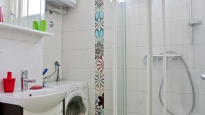 A bathroom with a washing machine, a sink, a toilet, and a glass-enclosed shower. - 4* studio apartment, simple and modern in the beautiful city of Split (Split)