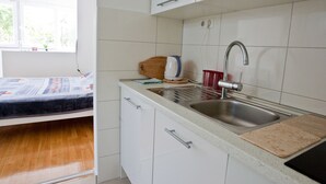 A small kitchenette with a sink, a kettle, and a cutting board. - 4* studio apartment, simple and modern in the beautiful city of Split (Split)