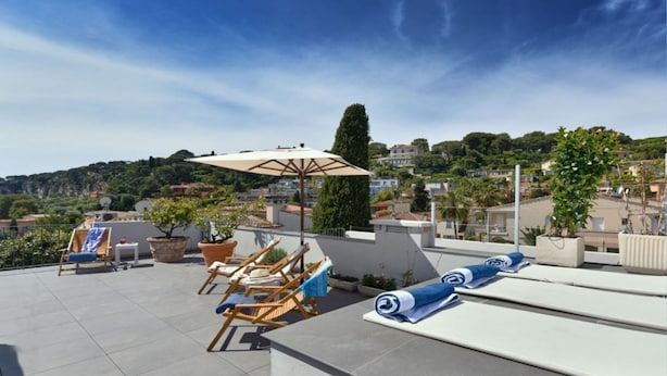 Terraza en la azotea con sillones, una sombrilla y plantas en macetas.