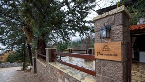 Un muro in pietra con un cartello di legno che riporta la scritta "Parnassos" e una recinzione in legno.