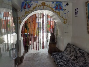 A cozy interior with a decorative archway, a sofa, and a statue. - Chelitos Backpacker (Cusco)