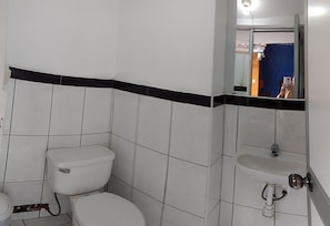 A bathroom with a toilet, sink, and mirror. - Chelitos Backpacker (Cusco)