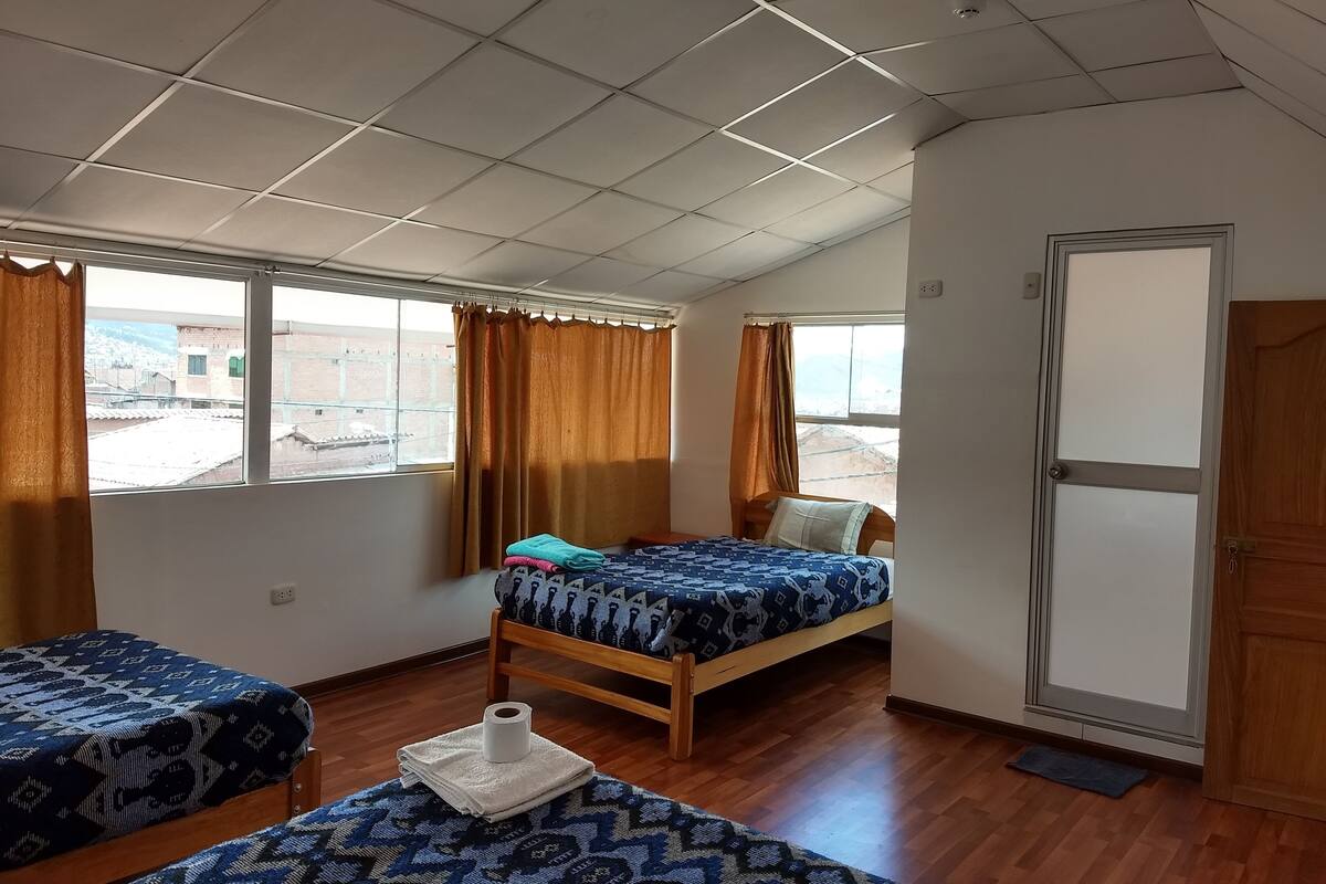 A room with two beds, a wooden door, and a window with curtains.