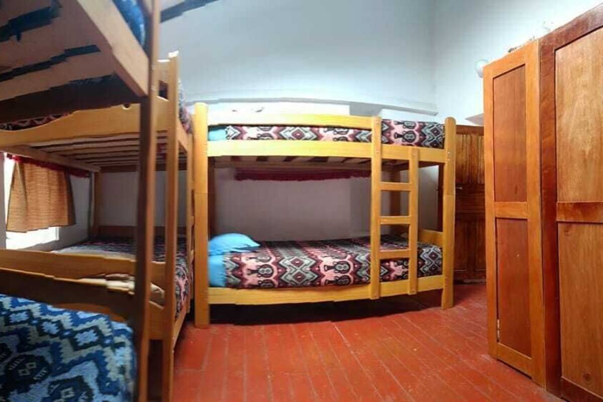 A room with bunk beds, a wooden wardrobe, and a window with curtains.