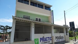 A two-story building with a green and white facade, featuring a sign for 'PRACTIC POSADA' and contact numbers. - Practic Pousada (Aparecida)