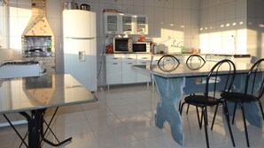 A modern kitchen with white cabinets, a microwave, and a gas stove. - Practic Pousada (Aparecida)