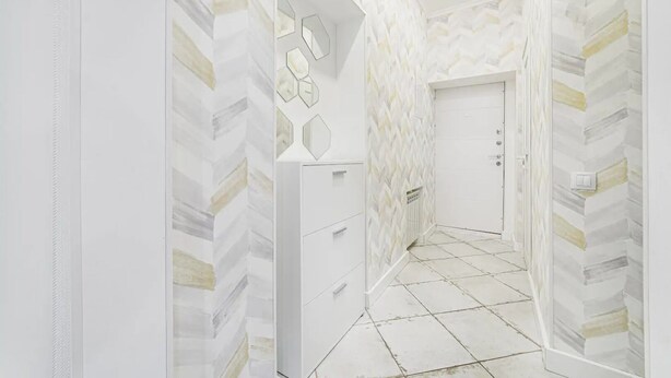 A hallway with a geometric patterned wall, a door with a handle, and a tiled floor. - Novus apartments in Odesa (Odes'ka oblast)
