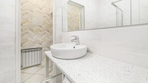 A modern bathroom with a large white sink, a mirror, and a herringbone patterned wall. - Novus apartments in Odesa (Odes'ka oblast)
