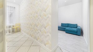 A modern room with a patterned wall, a blue sofa, and a small table with chairs. - Novus apartments in Odesa (Odes'ka oblast)