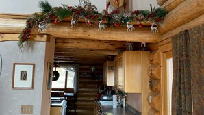 L’intérieur d’une cabane en rondins comprend une cuisine, un coin repas et un couloir menant à une chambre.