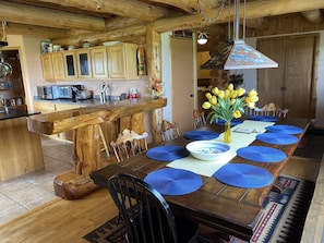 Enjoy meals in this inviting dining area with a wooden table and chairs, surrounded by a kitchen with wooden cabinets.