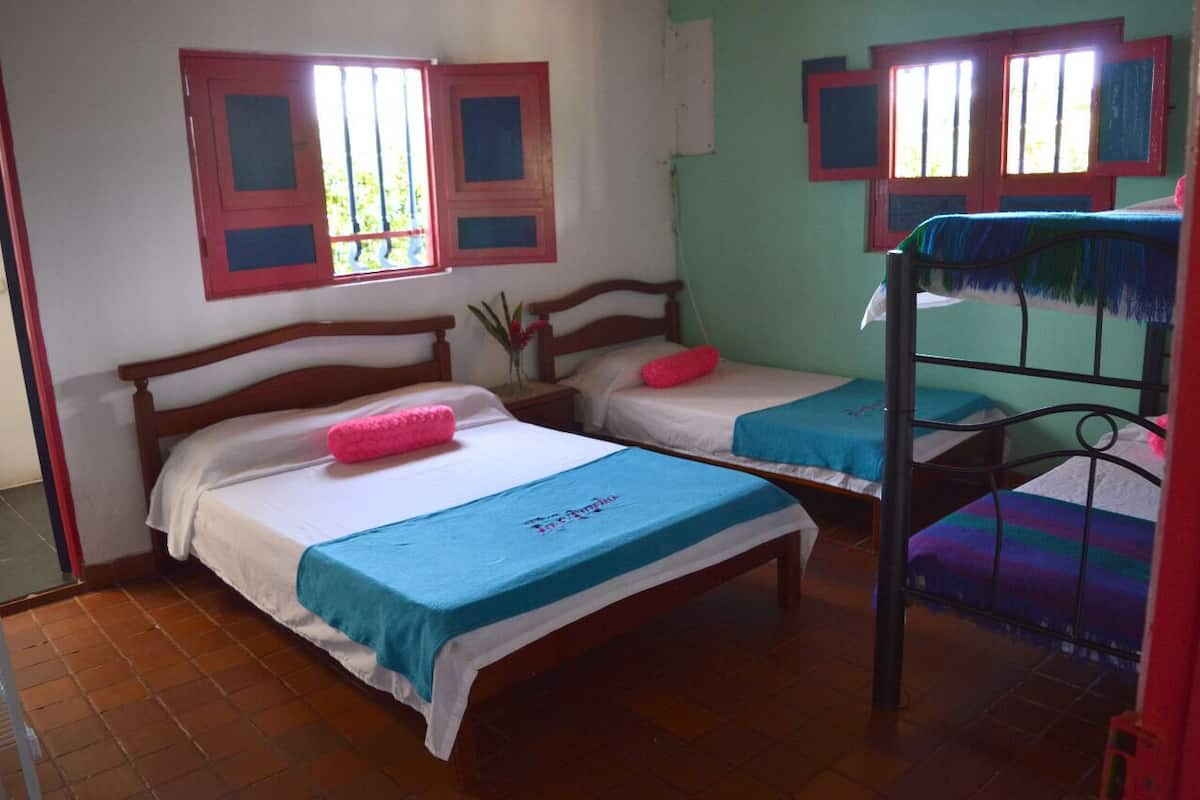 Quarto com duas camas de madeira, uma com colcha azul e a outra com almofada rosa.