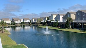 Un quartiere residenziale con un elemento d'acqua tranquillo, case con balconi e cielo sereno.
