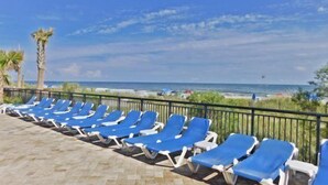 Un área de descanso frente a la playa con sillones azules y vista al océano.