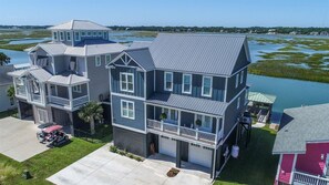 A multi-story house with a large front porch, a garage, and a boat dock.