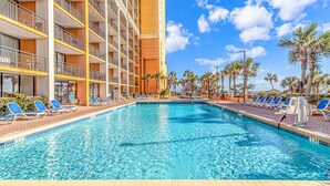 Ein Hotelpool mit Liegestühlen und Palmen.