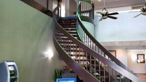 A modern interior with a spiral staircase, a Bud Light sign, and a payment machine.