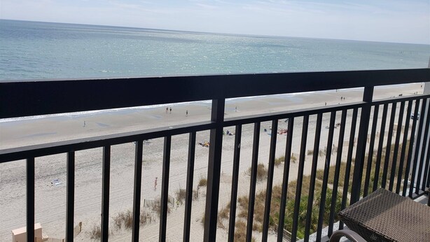 A balcony with a view of a beach and ocean.