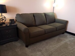 A brown sofa with a matching side table, a lamp, and a telephone. - Sun N Sand 811 (Myrtle Beach)