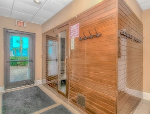 An entrance with a glass door, a wooden wall, and an exit sign.