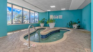 A small indoor pool with tiled flooring, potted plants, and safety signs. - Landmark 830 (Myrtle Beach)
