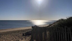 Een strand met een houten omheining, een boot en de oceaan.