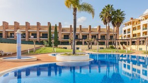 A swimming pool with a tiled edge, surrounded by palm trees and a building with multiple balconies. - Space and comfort in beautiful Vilamoura, Algarve, Portugal  (Vilamoura)