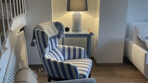 A living room with a blue armchair, a small table with a lamp, and a staircase. - Space and comfort in beautiful Vilamoura, Algarve, Portugal  (Vilamoura)
