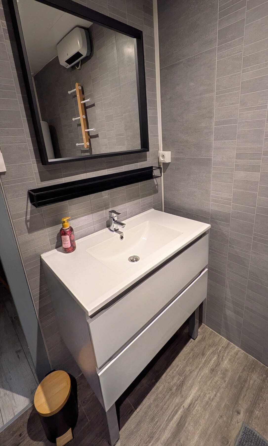 Un bagno moderno con un lavandino bianco, uno specchio e un erogatore di sapone.