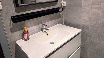 Un bagno moderno con un lavandino bianco, uno specchio e un erogatore di sapone.