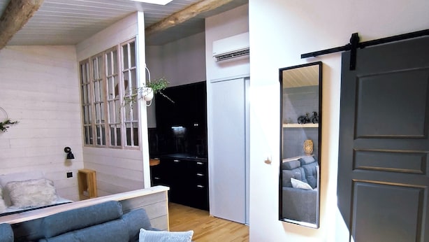 A modern living room with a sofa, a mirror, and a sliding door. - Appartement Lila (Carcassonne)