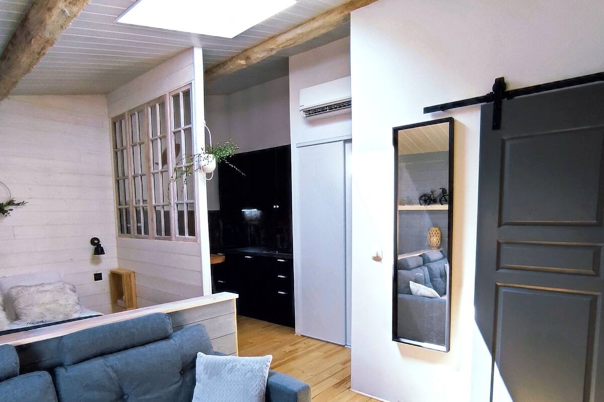 A modern living room with a sofa, a mirror, and a sliding door.