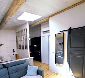 Een moderne woonkamer met een bank, een spiegel en een schuifdeur.