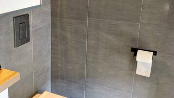A modern bathroom with a toilet, a towel rack, and a window.