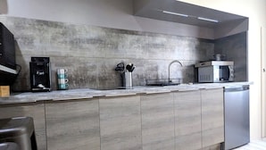 A modern kitchen with a built-in microwave, coffee machine, and stainless steel appliances. - Appartement Lila (Carcassonne)