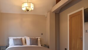 Un dormitorio con una cama, una puerta de madera y una lámpara colgante.