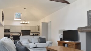 Una sala de estar moderna con un sofá gris, una mesa de centro de madera y un televisor de pantalla plana.