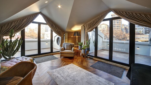 Uma sala de estar espaçosa com teto alto, janelas amplas e vista para a cidade.
