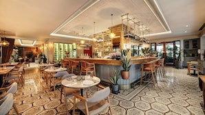 Restaurante com área de bar, cadeiras e mesas de madeira, e piso estampado.