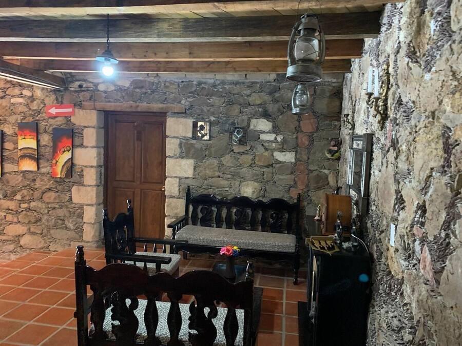 A rustic interior with stone walls, wooden benches, and a tiled floor.