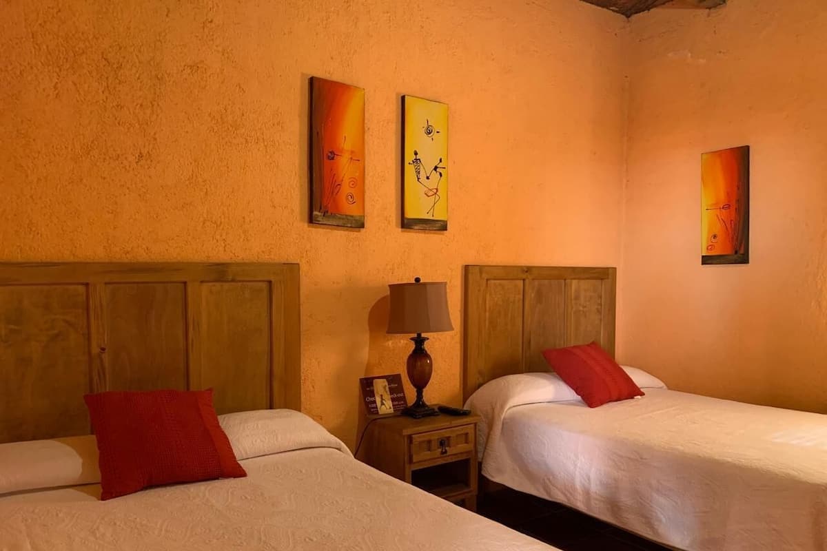A hotel room with two beds, wooden headboards, and artwork on the walls.